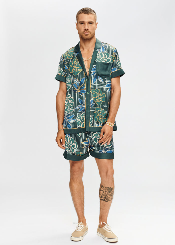Male model wearing a green Bahar Silk Shirt with tropical leaf print and matching shorts against a neutral background
