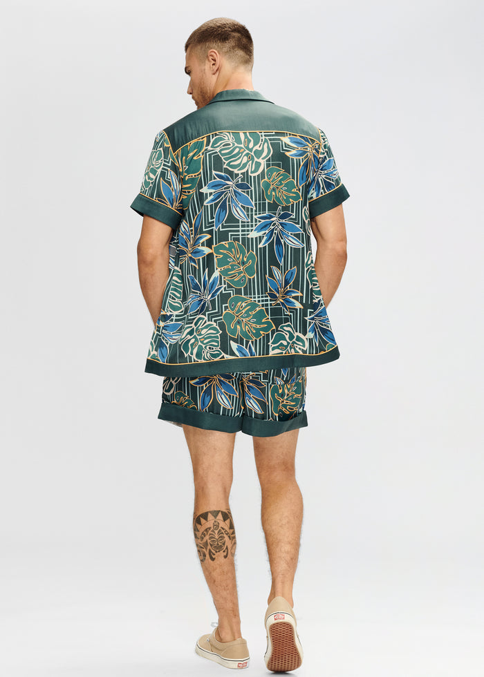 Back view of Bahar Silk Shirt in green tropical print with blue and gold leaves and rolled cuffs.