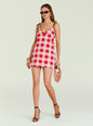Front view of Shantie Mini Dress in pink red gingham with brown shoulder ties, model wearing sunglasses and carrying a woven bag thumbnail image 5 of 5