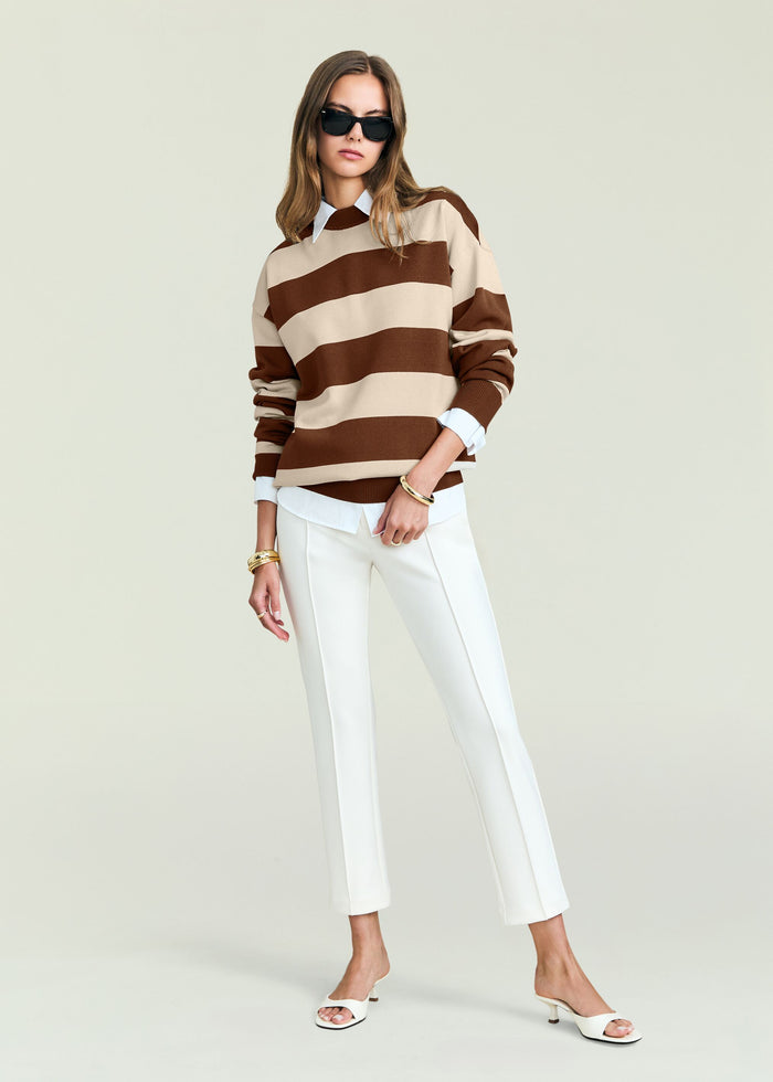 Model in Bryn Knit Sweater with bold beige and brown stripes over a white shirt, wearing sunglasses.