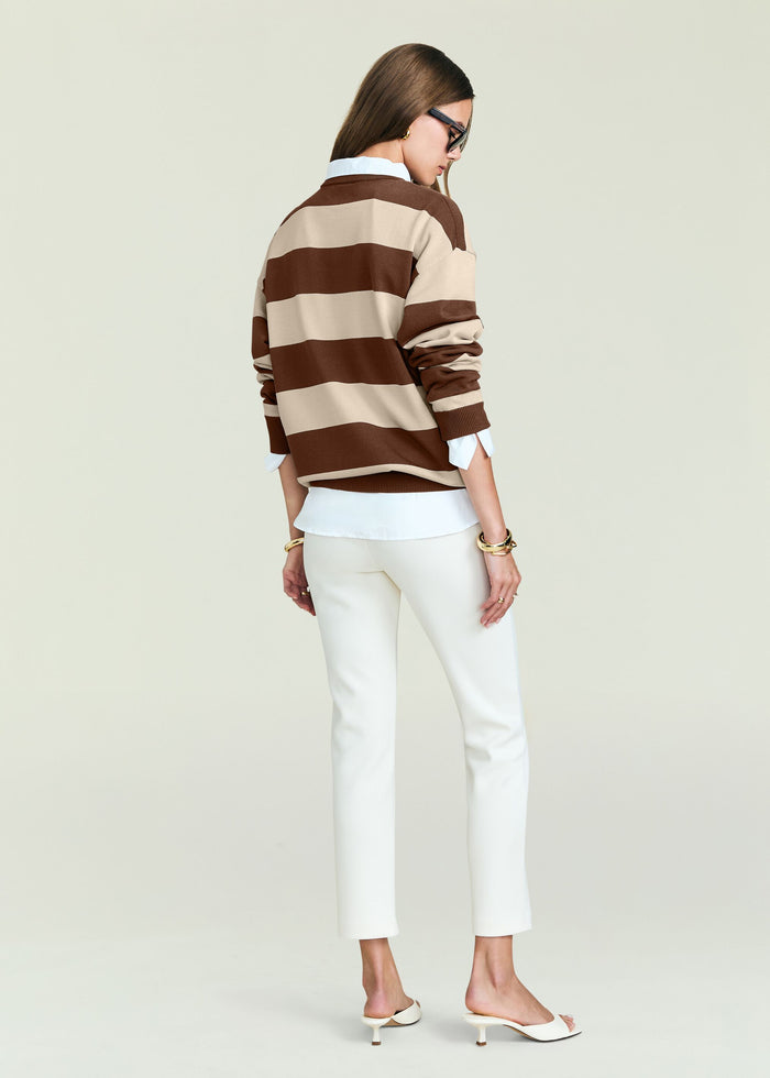 Back view of a brown and beige striped knit sweater worn over a white shirt with white pants