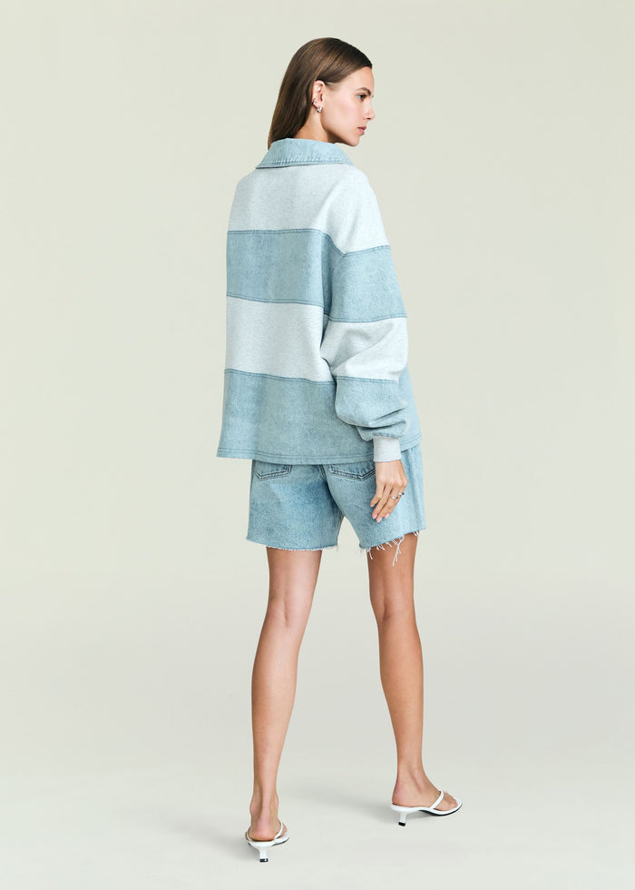 Back view of model wearing Cher Denim Top with horizontal light blue stripes and an oversized fit