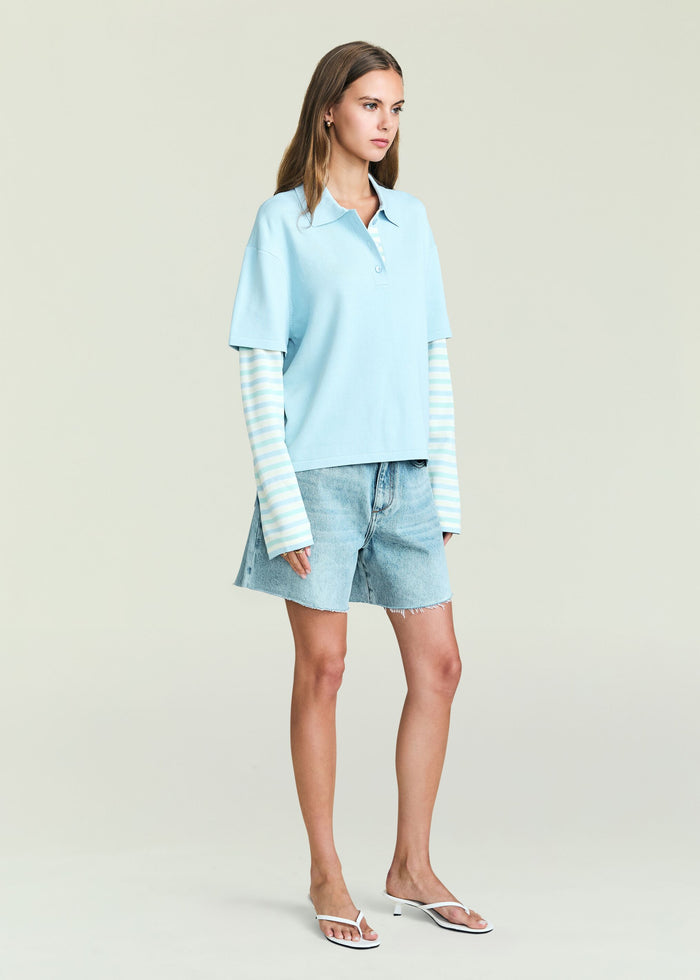 Emilee Top pale blue polo with striped long sleeve underlayer on a model wearing denim shorts.