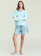 Model wearing Emilee Top in pale blue with a striped underlayer, arms crossed, paired with light wash denim shorts. thumbnail image 2 of 5
