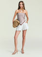 Model wearing a strapless satin top with a brown geometric print, white shorts, and a woven straw bag. thumbnail image 2 of 5