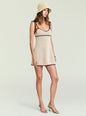 Side view of model in beige crochet mini dress with brown trim and shoulder tie straps, wearing a woven hat thumbnail image 3 of 5