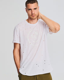 Model wearing a white Noah Easy T-Shirt with scattered brown specks.