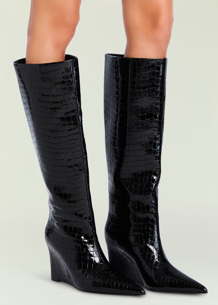 Two black crocodile-embossed knee-high boots with glossy finish and chunky heels.