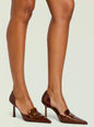 Brown patent pointed toe high heel with strap across the vamp on a model's feet thumbnail image 5 of 5