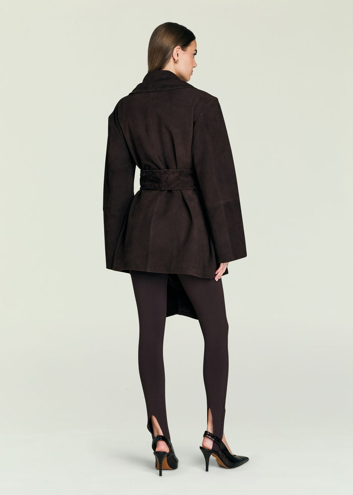 Back view of a dark brown suede jacket with a wide belt at the waist and oversized sleeves on a model.