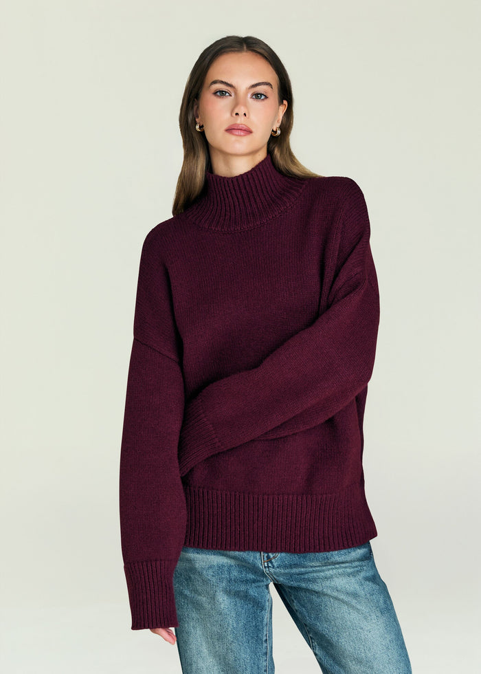 Model wearing a burgundy Elsa Turtleneck Sweater in a relaxed fit with ribbed cuffs and hem