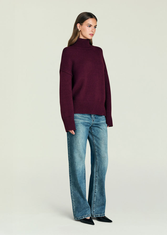 Elsa Turtleneck Sweater in deep burgundy on a model; oversized knit with ribbed cuffs and hem.