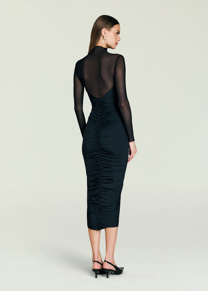 Back view of a model in the black Emilyn Midi Dress with sheer mesh back and long sleeves.