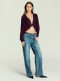 Model wearing burgundy Jerome Top with twisted front knot and long sleeves, paired with blue jeans. thumbnail image 2 of 5