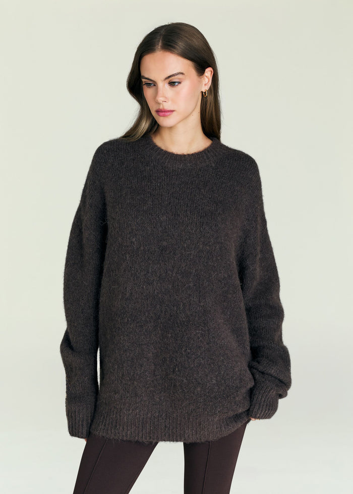 May Sweater worn by a woman in a dark fuzzy knit against a pale background.