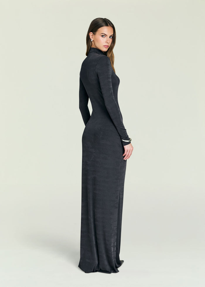 Side view of a model in a dark Kim Maxi Dress with a coat draped over her shoulders