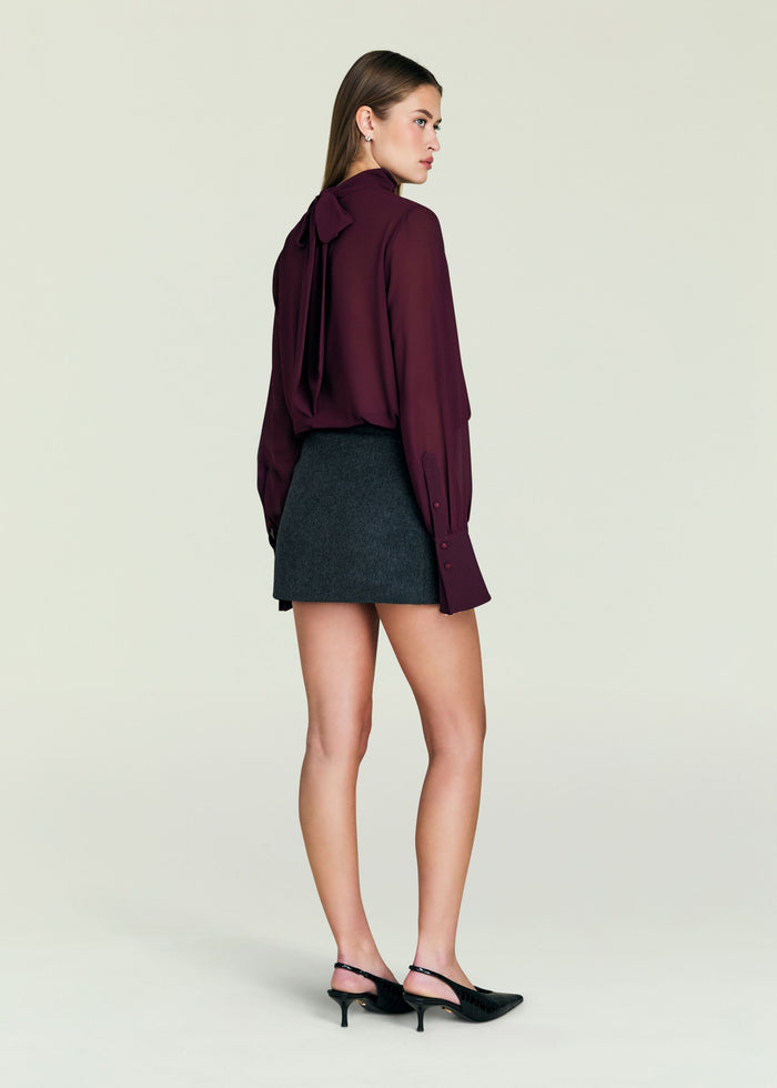 Back view of the Usha Wool Skirt on a model paired with a burgundy blouse.