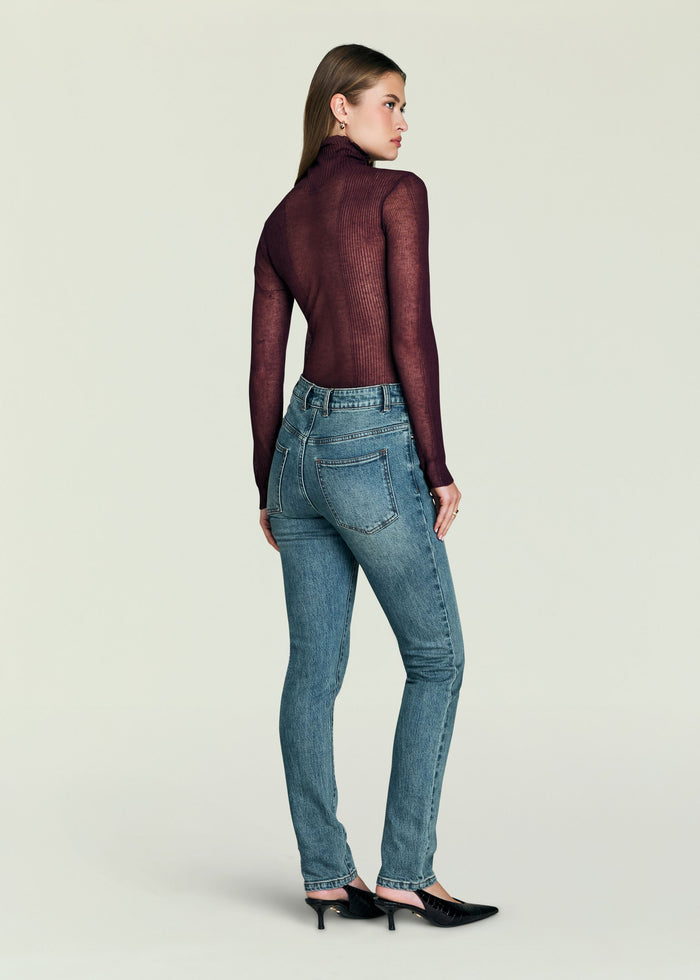 Back view of a model wearing Celia High Rise Skinny Jeans with a burgundy knit top.
