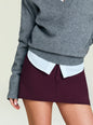 Close-up of gray V-neck sweater layered over a white shirt with a burgundy mini skirt. thumbnail image 3 of 4