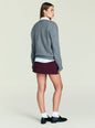 Back view of a model wearing a gray knit sweater over a white shirt and a burgundy mini skirt. thumbnail image 4 of 4