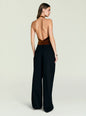 Back view of a model in a copper velvet halter bodysuit tied at the waist with black wide-leg pants. thumbnail image 4 of 5