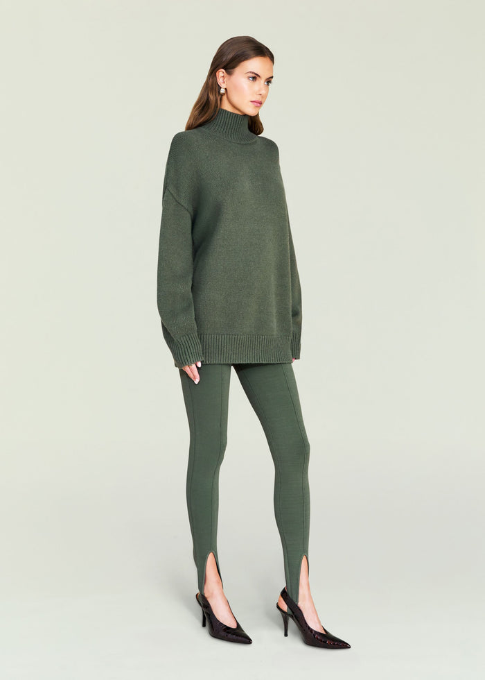 Model wearing olive green Kelsey Stirrup Leggings paired with an oversized knit sweater