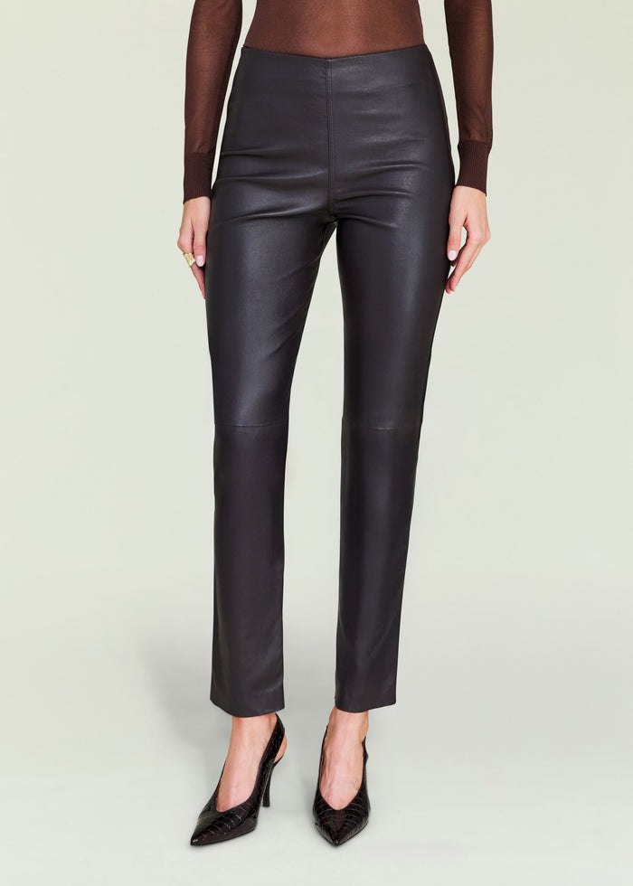 Front view of a model wearing Cyra Leather Legging in black leather with a high waist and pointed heels.