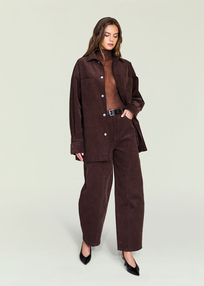 Model wearing a dark brown corduroy suit with an oversized jacket, wide-leg pants and a belt.