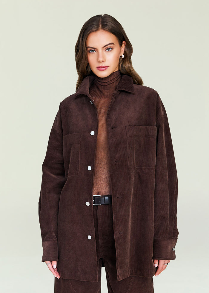 Front view of April Corduroy Shacket worn open over brown turtleneck, belted corduroy pants.