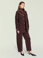 Model wearing an oversized dark brown corduroy shacket with large patch pockets and silver buttons over a brown turtleneck. thumbnail image 2 of 5