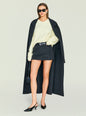Front view of the cream Alejandra Sweater styled with a dark coat draped over the shoulders and sunglasses. thumbnail image 5 of 5