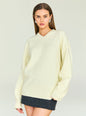 Model wearing cream Alejandra Sweater with a relaxed fit and V neckline, accessorized with silver earrings. thumbnail image 1 of 5