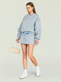 Model in a gray Taley Sweatshirt with a matching mini skirt white socks and sneakers, carrying a beige bag thumbnail image 5 of 5