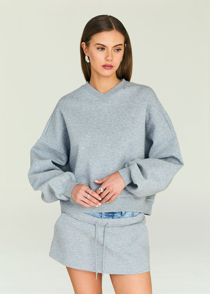 Model wearing a grey Taley Sweatshirt with a relaxed fit and ribbed cuffs