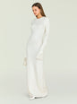 Side view of a model wearing the cream knit Carina Maxi Dress with fringe cuffs and a small handbag. thumbnail image 5 of 5