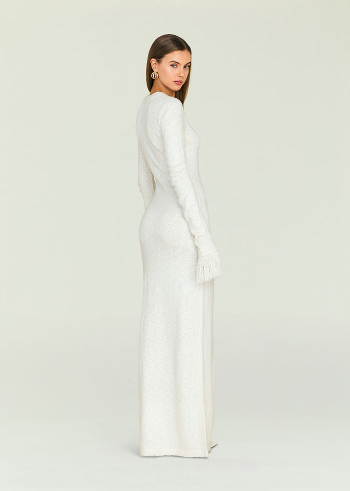 Side profile of a model in the cream knit Carina Maxi Dress with fringe cuffs.
