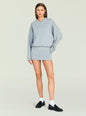 Model wearing a light gray Dionne Mini Dress with a roomy sweatshirt top and a fitted mini skirt against a pale backdrop thumbnail image 1 of 5