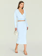Front view of a model in a light blue wrap knit top with a deep V neckline and matching knit skirt, holding a cream bag. thumbnail image 5 of 5