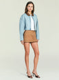 Model wearing a cropped light denim Coop Jacket with brown leather collar over a white top and tan skirt. thumbnail image 4 of 5