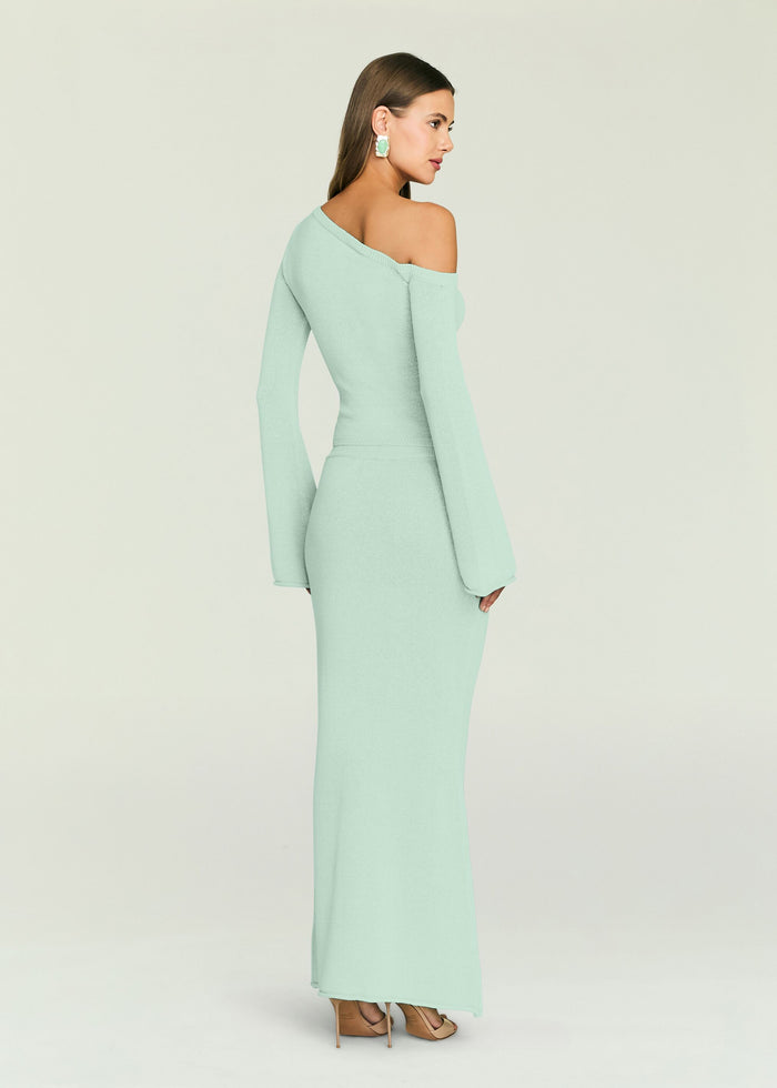Back view of a model wearing a mint knit maxi dress with an off‑the‑shoulder neckline and long sleeves.