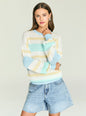 Model in a pastel striped oversized knit sweater with blue cream and yellow tones. thumbnail image 1 of 5
