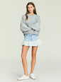 Model wearing a light wash denim mini skirt with a wide waistband over a gray oversized sweatshirt. thumbnail image 2 of 5
