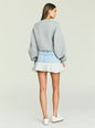 Back view of a model wearing a gray oversized sweatshirt and light wash color-block denim mini skirt. thumbnail image 5 of 5