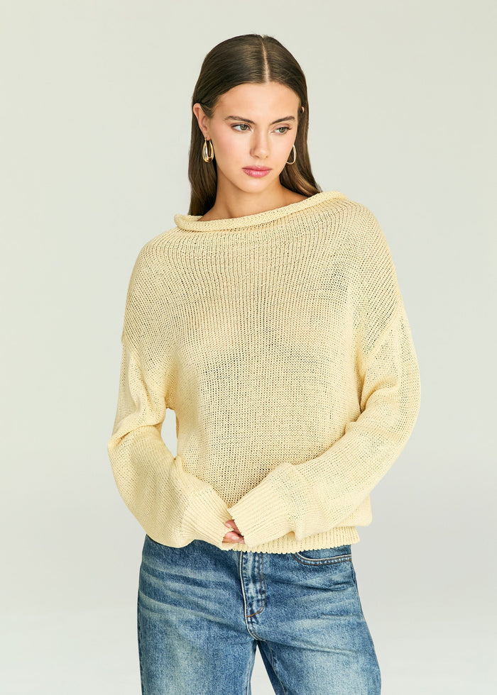 Woman wearing Oro Knit Sweater in soft beige with a loose knit and relaxed silhouette.