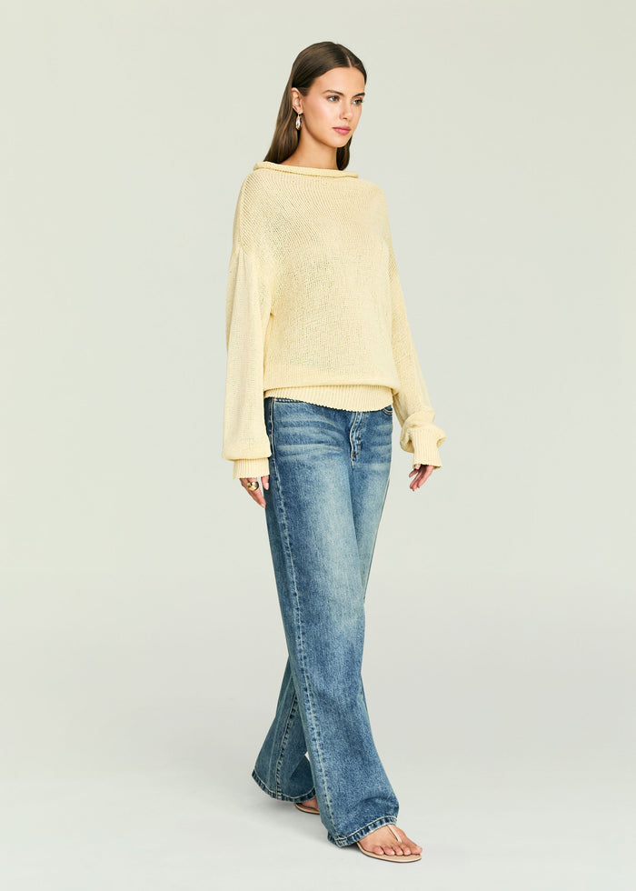 Model in Oro Knit Sweater in pale beige with an oversized fit and relaxed drape, paired with denim jeans.
