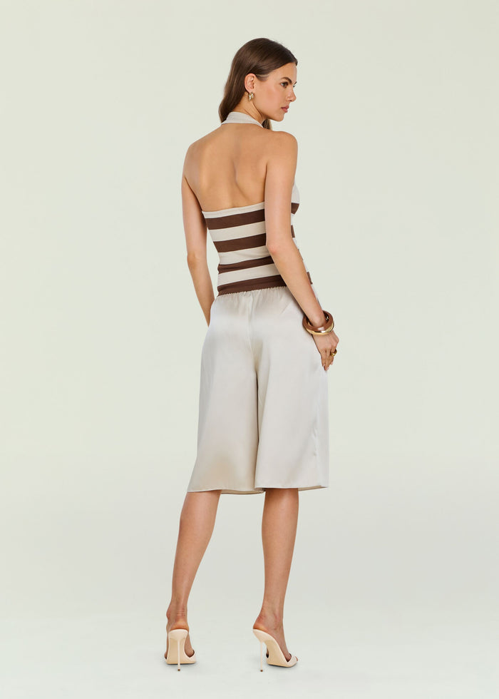 Back view of Amira Knit Tank halter neck sleeveless knit top featuring wide beige and brown stripes and light trousers.