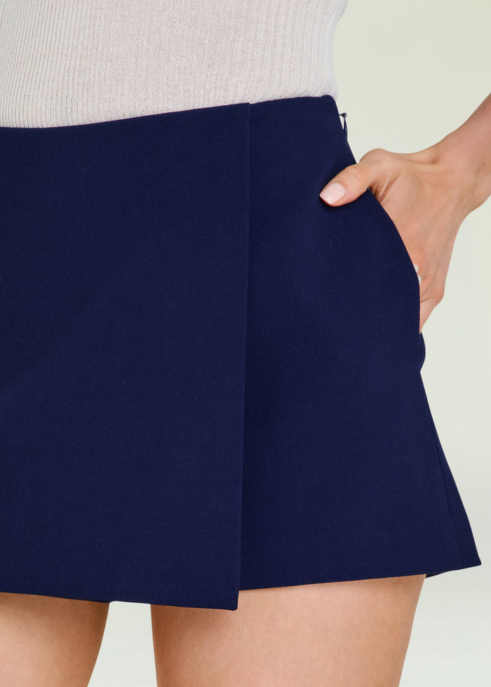 Close-up of navy Deenie Skort showing its waistband and pocket with a model's hand in the pocket