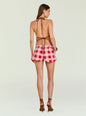 Back view of a woman in a brown halter top tied at the neck and back, wearing red and white gingham shorts and brown sandals. thumbnail image 4 of 5