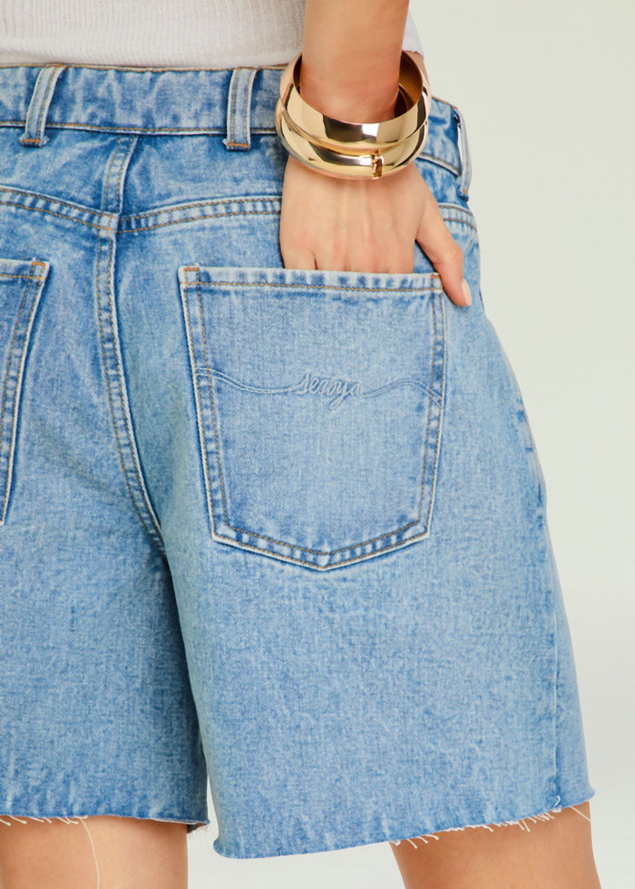 Back view of Sabrina Boyfriend Short denim shorts with hand in pocket and a chunky gold bracelet.
