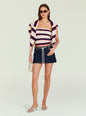 Front view of a model in a red navy white striped halter top with a striped blazer draped over shoulders, dark denim mini skirt, and a cream handbag. thumbnail image 2 of 5